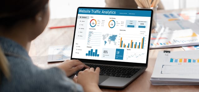 A person analyzing website traffic data on a laptop displaying graphs and charts
