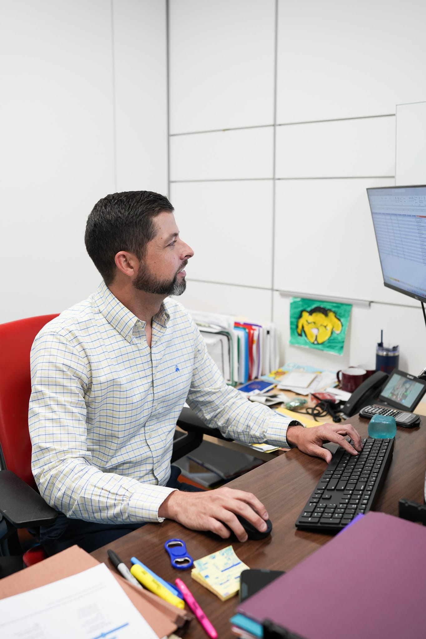Man sitting at a desk using a computer in an office setting.