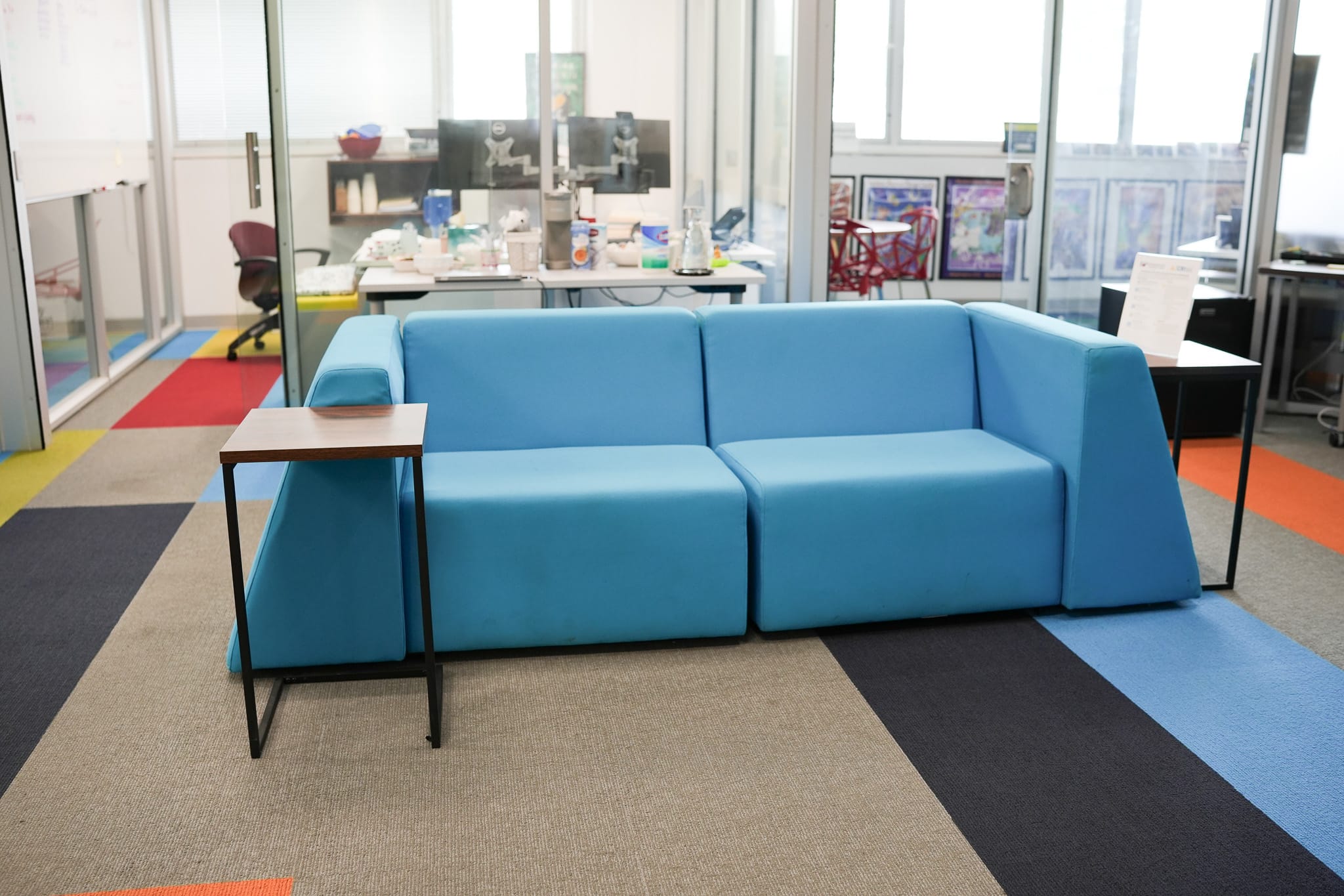 Modern office lounge area with blue couch and collaborative workspace