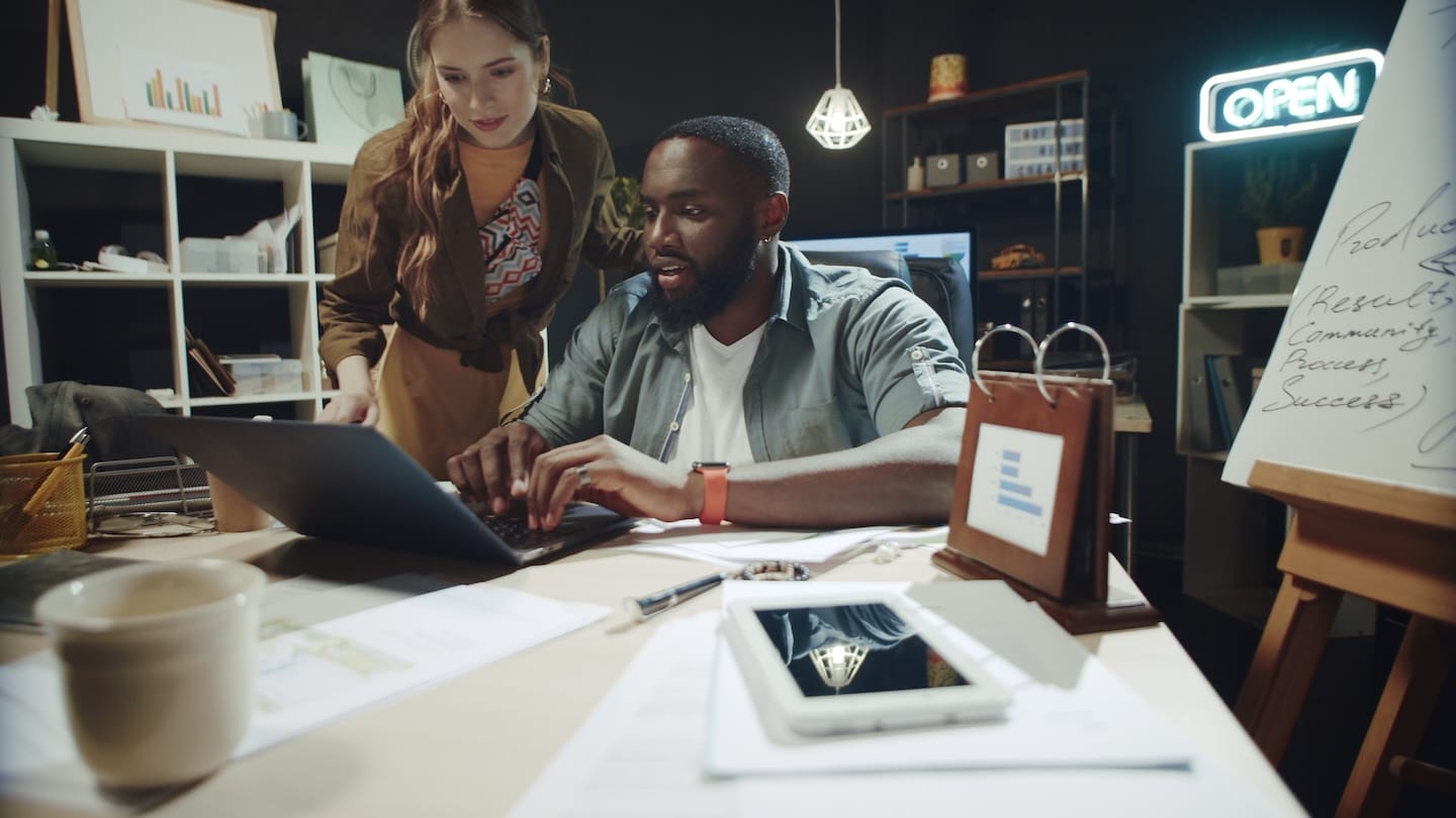 Two colleagues collaborating at a desk in a modern office