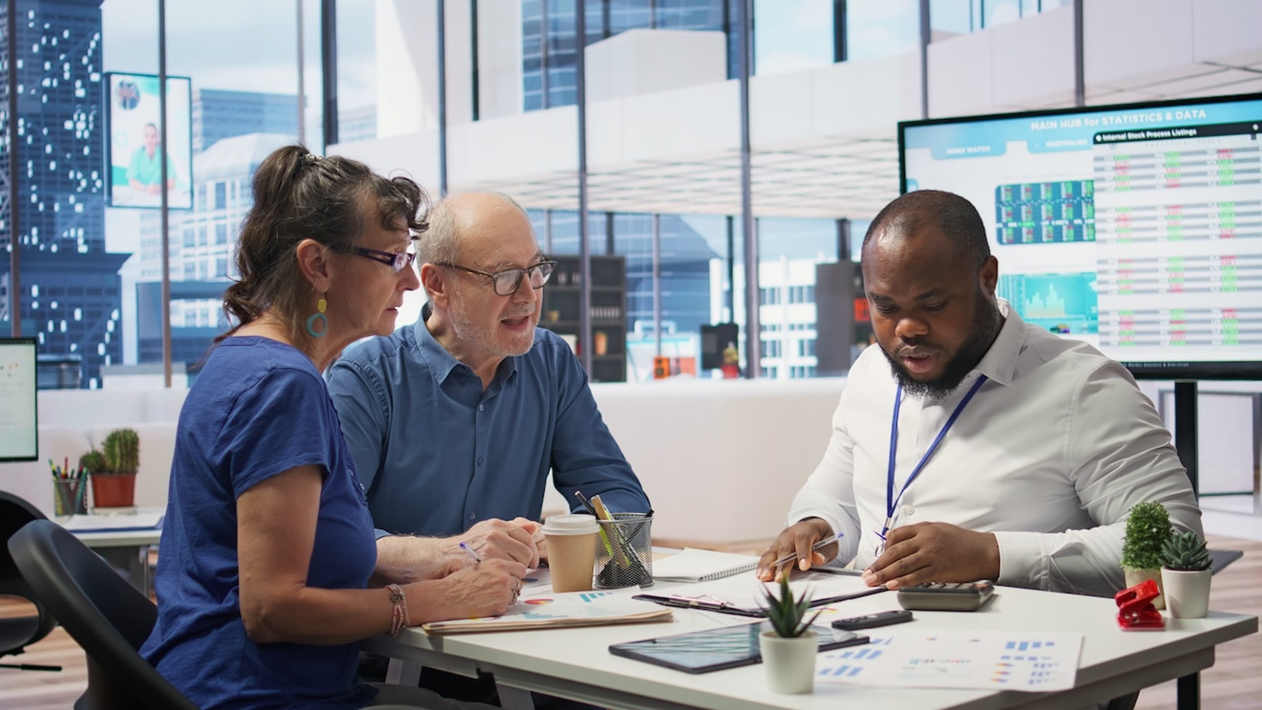Three professionals having a discussion at a table in a modern office.