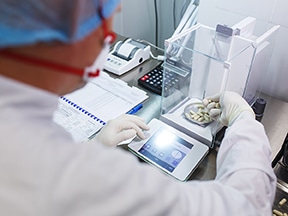 Scientist weighing capsules on a precision balance in a laboratory