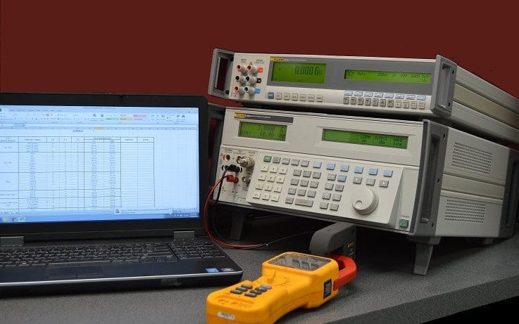 Michelli calibration technician operating electronic test instrument calibration equipment on a lab bench