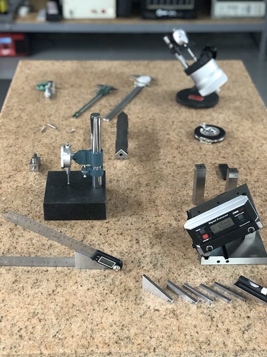 Precision dimensional measurement devices including calipers, indicators, and gauge blocks laid out for calibration