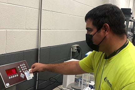 Michelli Weighing & Measurement technician performing calibration or repair work in an industrial environment