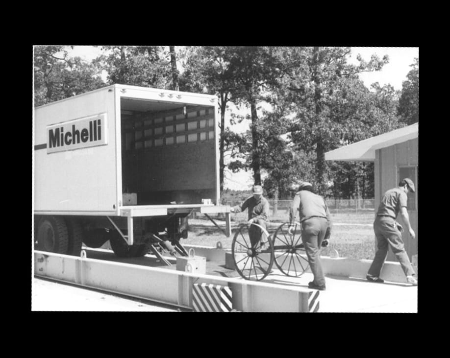Michelli technician performing startup and final calibration on a truck scale using a rented lift-gate truck and portable weights, circa 1977