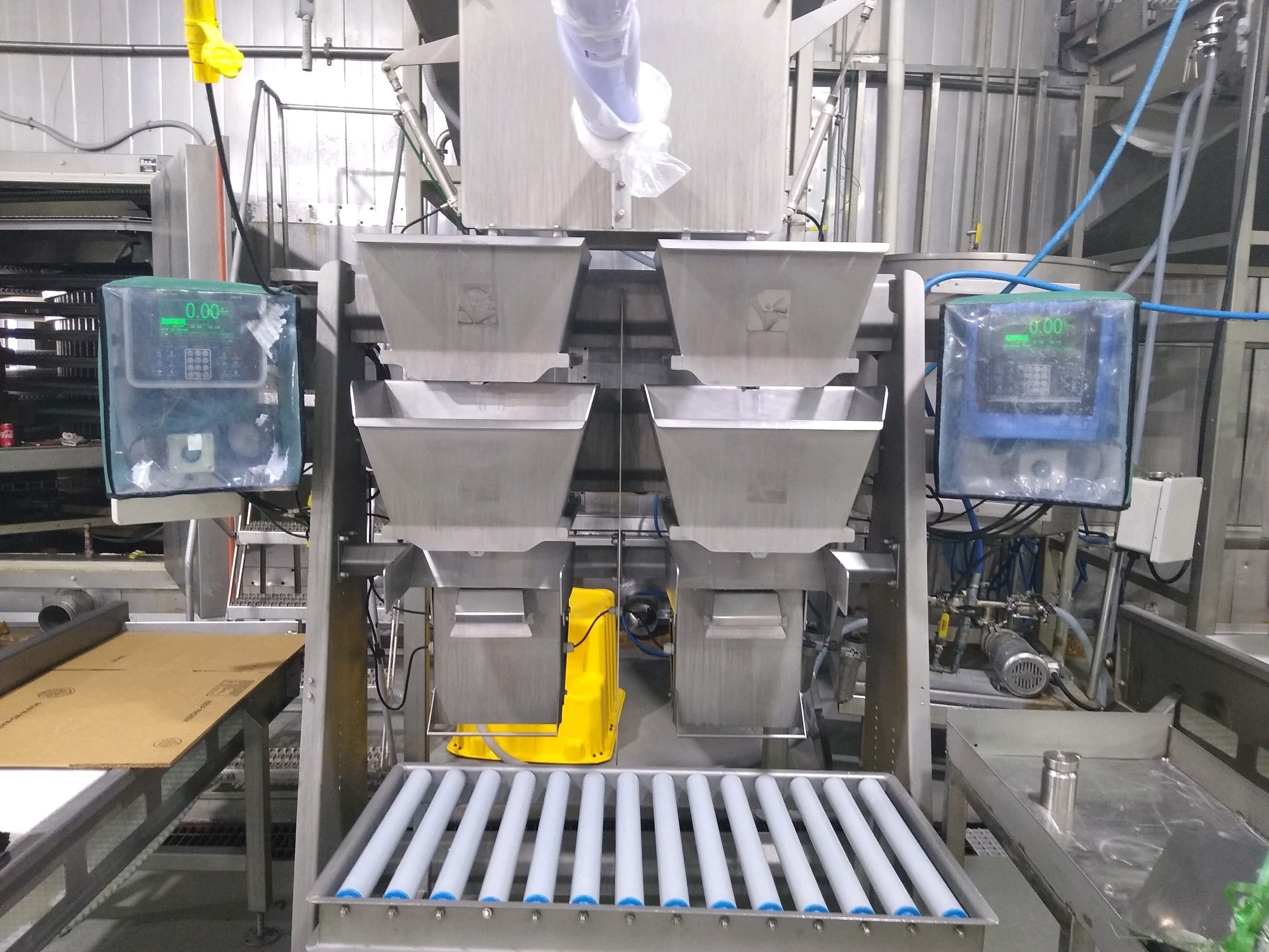 A large industrial weighing and filling machine with digital displays and multiple hoppers in a factory setting