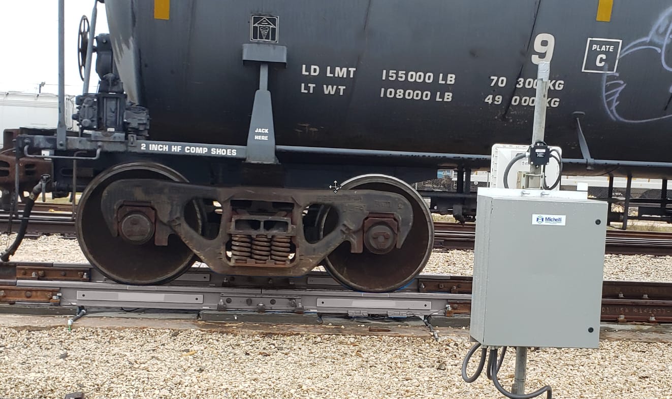 Close-up of a train wheel on tracks with a control box nearby