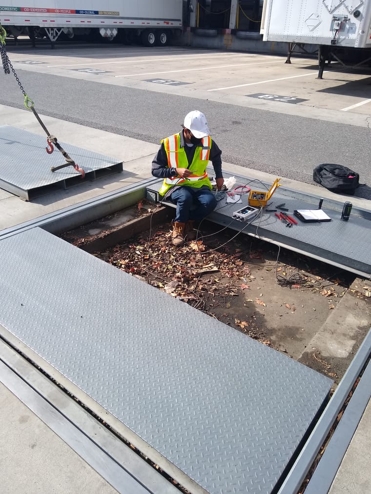 Technician inspecting a truck scale at a loading dock