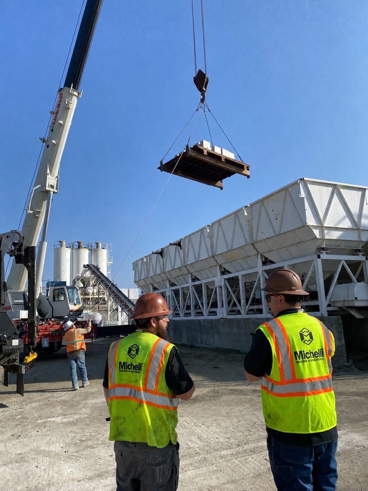 Construction workers in safety vests overseeing crane operation at a job site