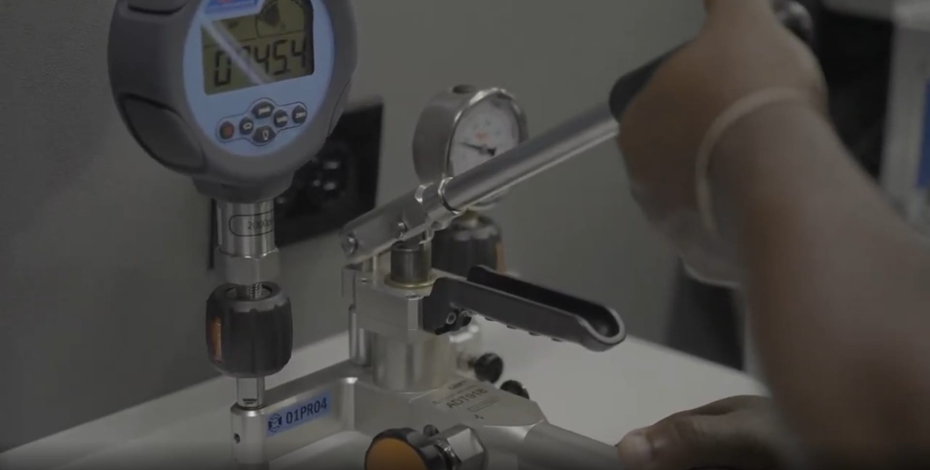 A person uses a digital and analog gauge for calibration purposes.