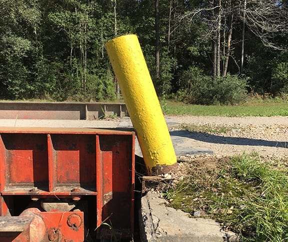 A bent truck scale guide post leaning against the scale platform, adding false weight