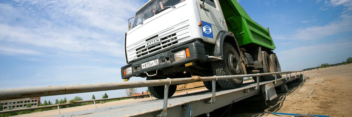 A large dump truck positioned on an industrial truck scale platform for weighing