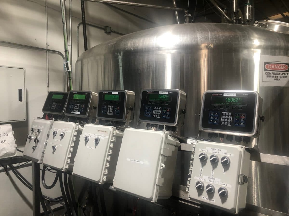 Industrial control panels mounted on stainless steel brewing tanks in a production facility