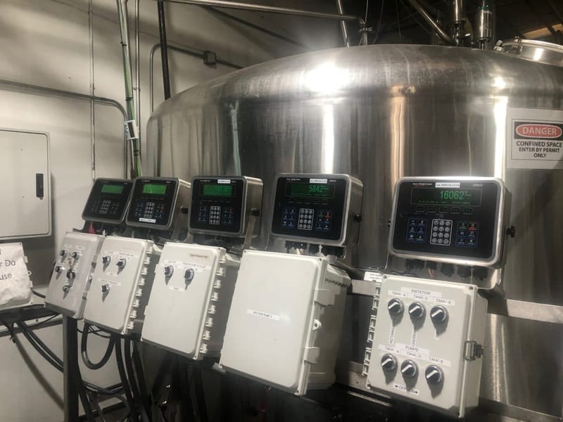 Industrial control panel screens mounted on a stainless steel brewing tank