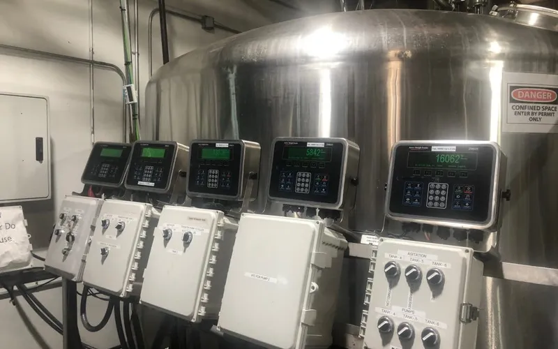 Industrial control panel screens mounted on a stainless steel brewing tank