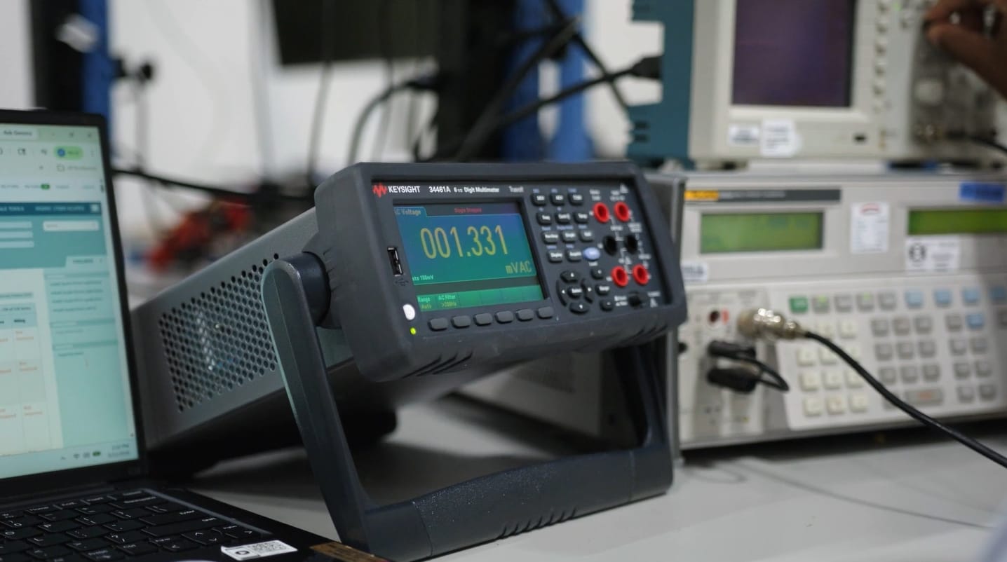 A multimeter displaying a reading of 001.331 mV AC on a lab bench with other equipment.