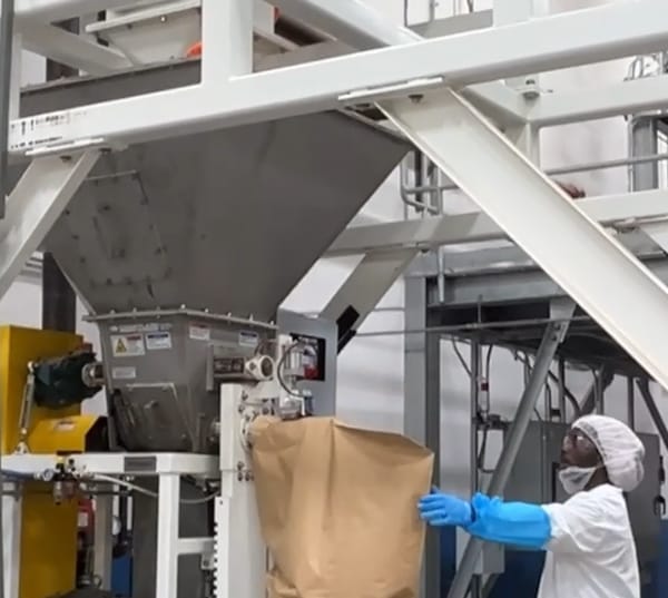 Worker operating industrial hopper and packing machine in a manufacturing facility