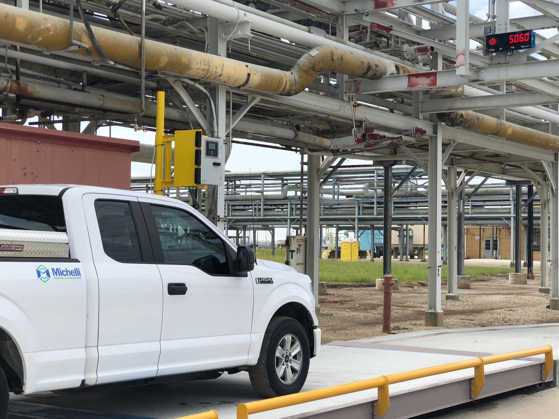 White truck on an industrial weighbridge with digital weight display reading 5060