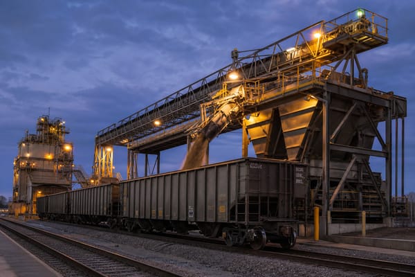Industrial hopper and conveyor system loading bulk material into a rail car at a terminal transfer facility