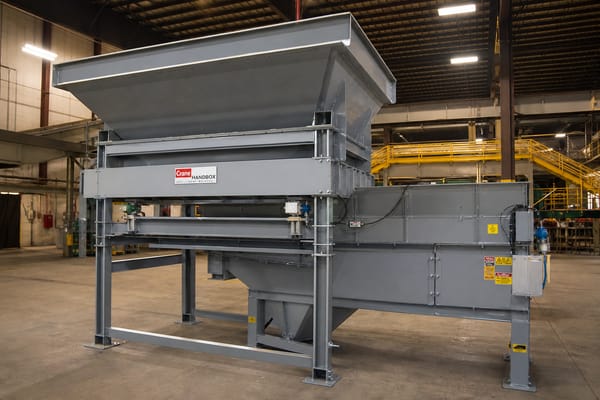 Heavy steel hopper scale with surge bin and diverter gate assembly in an industrial warehouse