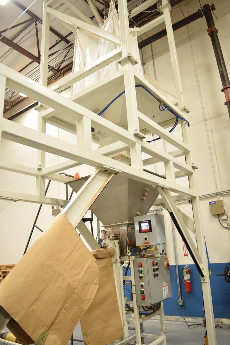 Industrial packaging machine with paper bags and control panel in a bulk filling factory