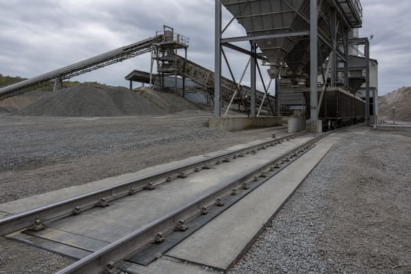 Heavy-capacity rail scale at an aggregate quarry site with hopper bins and conveyor structures