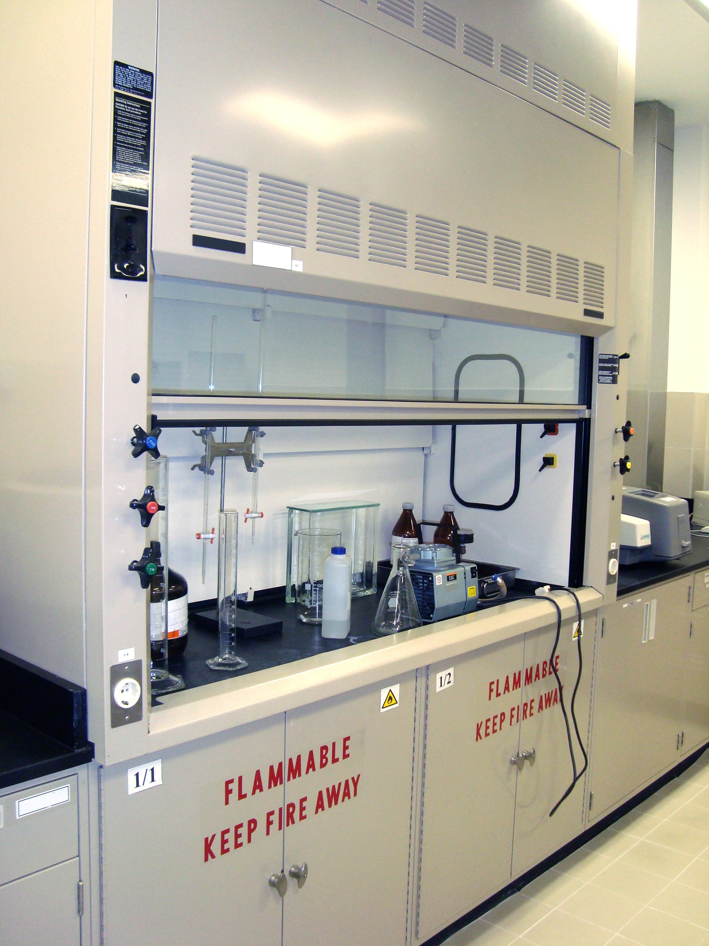 A laboratory fume hood containing various glassware and bottles
