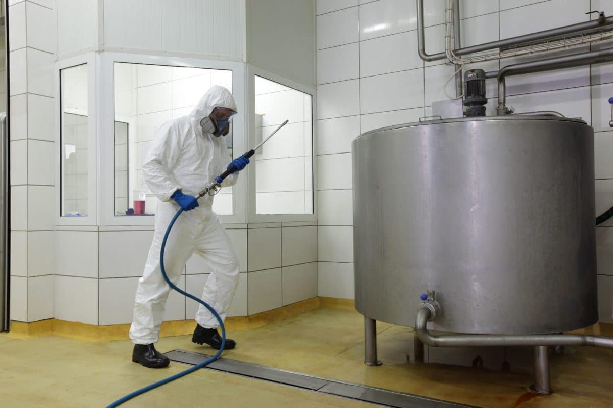 worker with a high pressure washer prepares to clean washdown scales