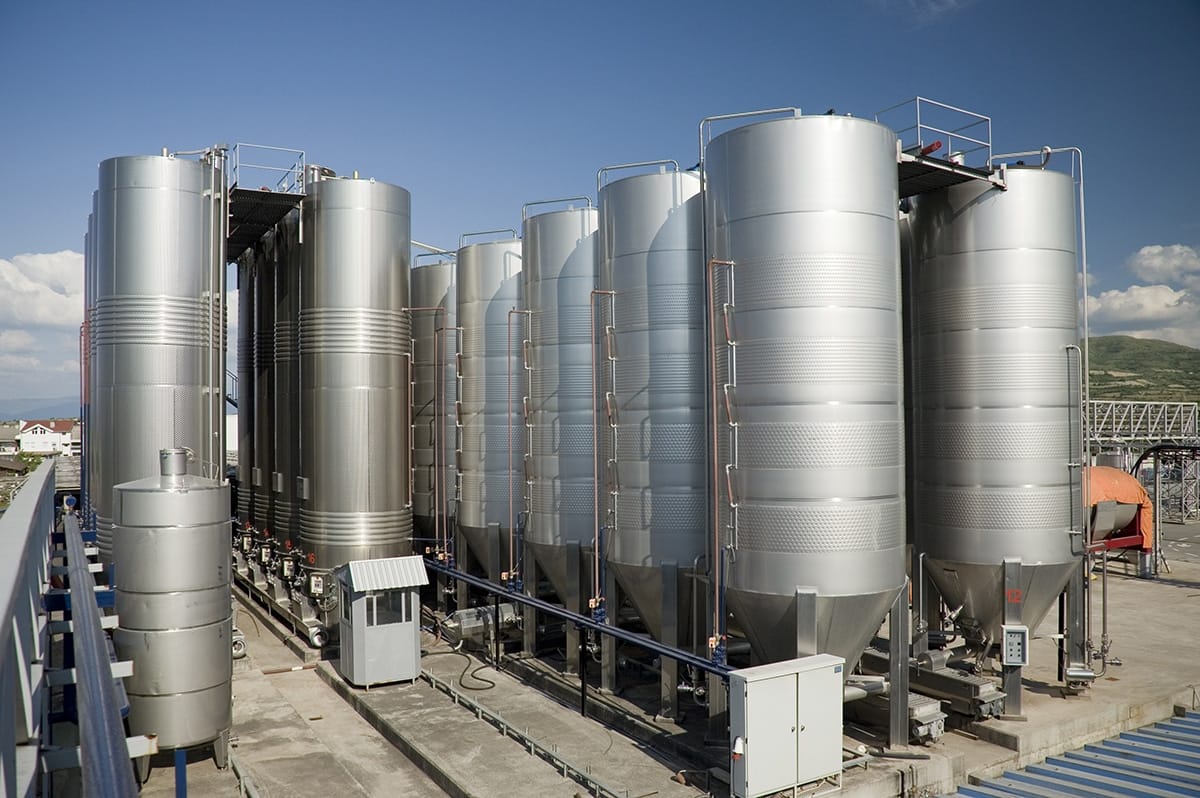 Industrial tanks and hoppers in a chemical processing facility used for material storage, inventory monitoring, and transfer control