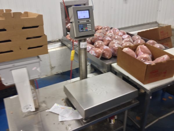 Industrial scale with packaged meat products on a table in a food processing facility
