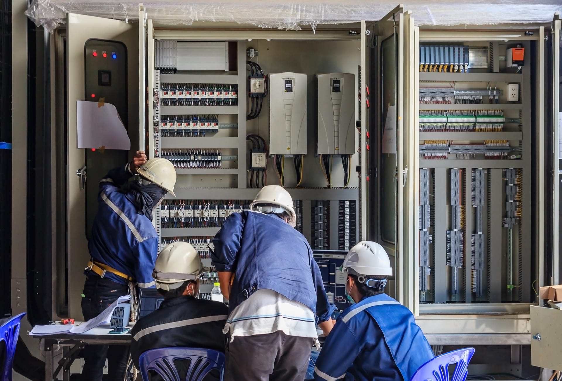 Technicians analyzing an electrical control panel for PLC and network integration