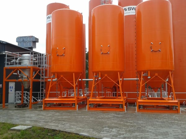 Row of orange industrial silos used for material storage and tank monitoring