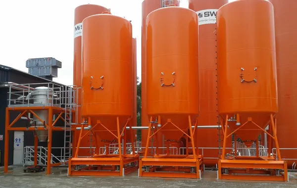 Row of orange industrial silos used for material storage and tank monitoring