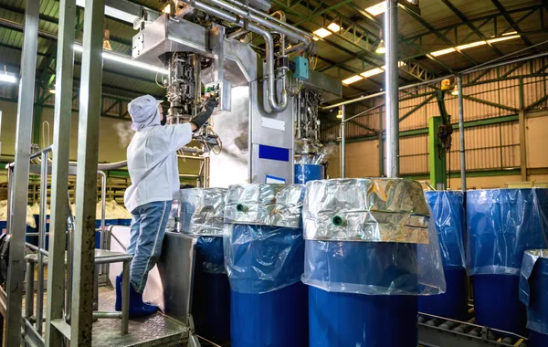 Worker operating machinery in an industrial facility representing liquid, drum, and tote filling applications