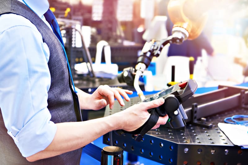 Engineer operating a robotic arm with a handheld control device representing a partnered OEM system with integrated support