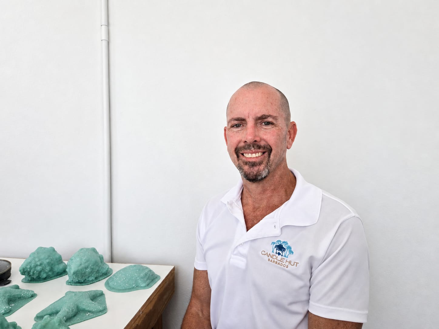 Candle Hut Barbados founder Michael Franco beside green ocean-form candle molds in the workshop.