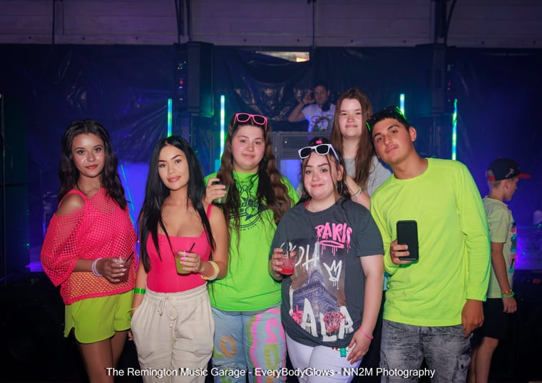 Six young people in bright neon attire at a party indoors