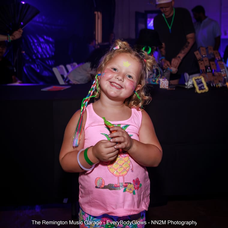 A child with face paint and braids at a glow-themed event