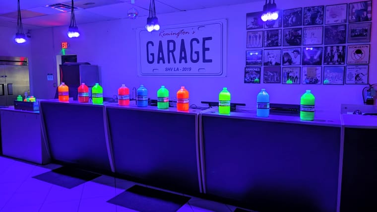 Fluorescent liquids glow in various colors under UV lights on a counter