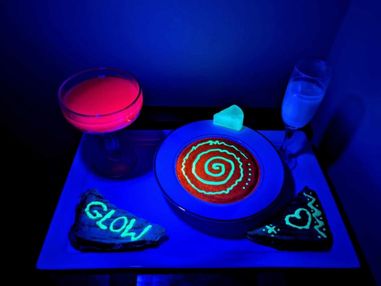 A tray with glowing food and drinks under UV light