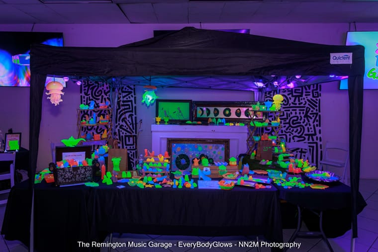 Neon-colored items displayed under a canopy with blacklight illumination