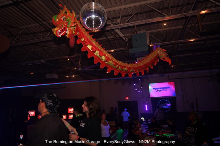 A decorative dragon hangs from a ceiling next to a disco ball at an indoor event