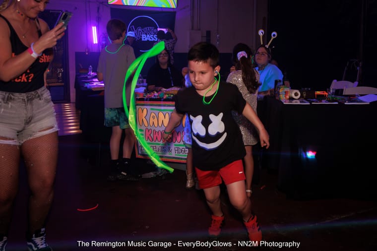 A child with a glow stick dances at a colorful indoor event
