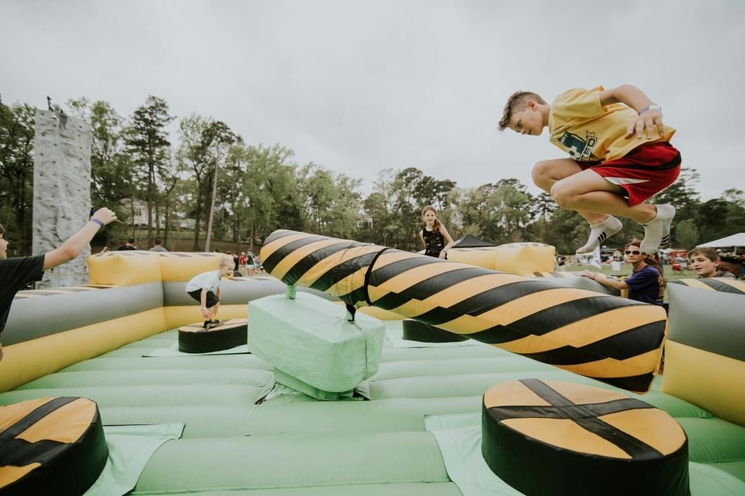 Children playing on an inflatable obstacle course outdoors.
