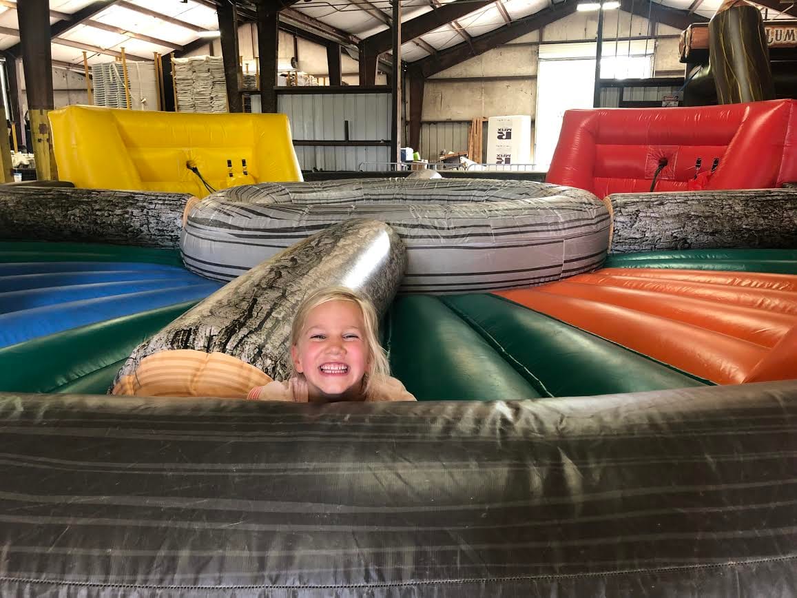 Smiling child inside an inflatable play structure with colorful sections.